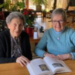 A photo of Marilyn Lavin and Nancy Hodges seated at a table with a book.